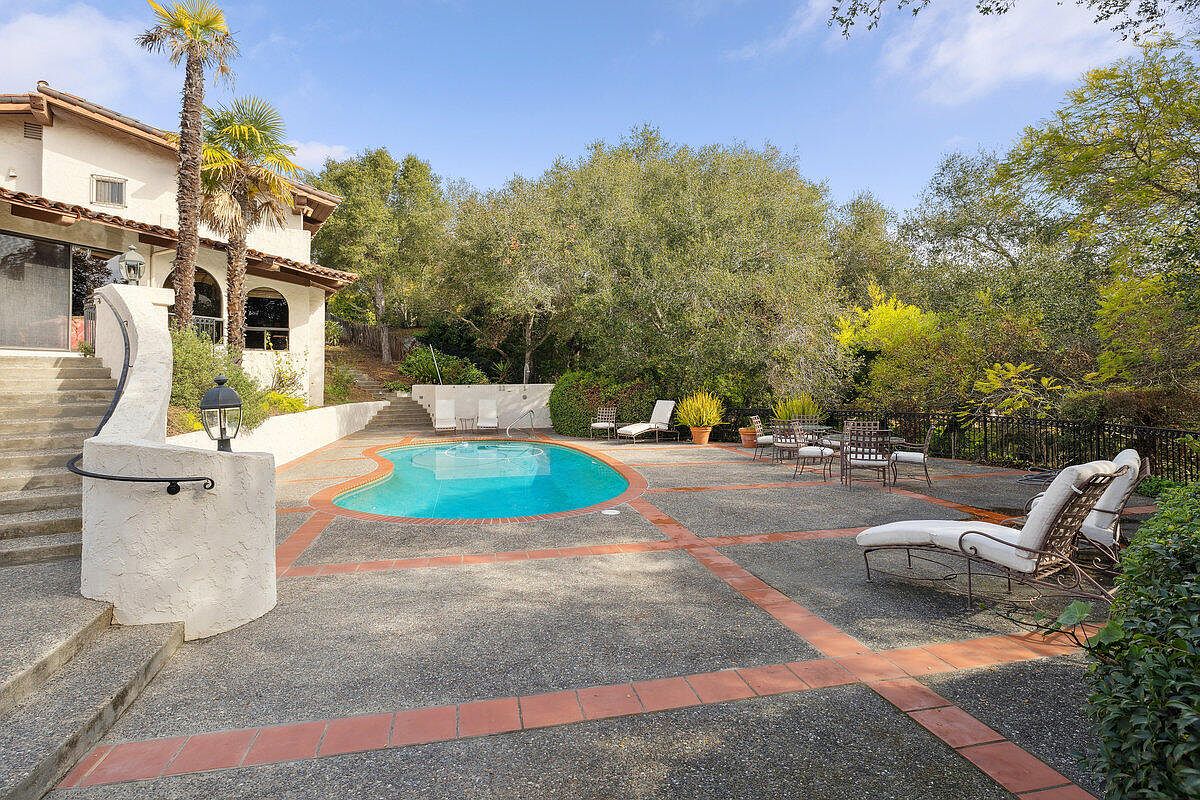 Pool and patio set among mature oaks.