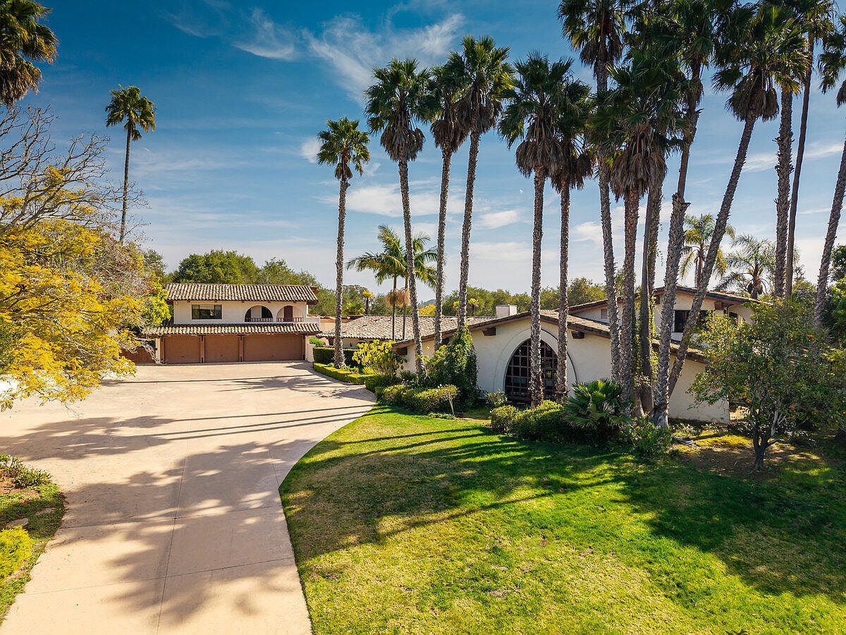 Aerial approach to 3978 Laguna Blanca Drive, a Hope Ranch estate framed by mature palms with a sweeping motor court and landscaped grounds.